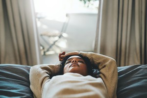 Tracking menstrual cycle-fertility awareness-ovulation-Cropped shot of a young woman lying on her bed with her eyes closed