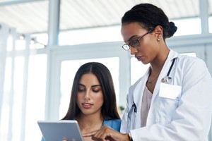 Shot of a young doctor using a digital tablet during a consultation with her patient