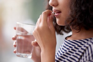 Cropped shot of an unrecognizable teenage girl drinking medication