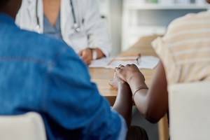 Closeup shot of a couple holding hands during a consultation with a doctor